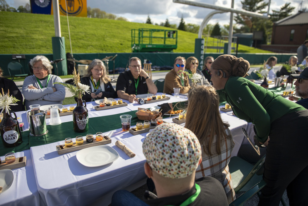 A student placing down food in front of someone who is at the Taste of Brewing event.