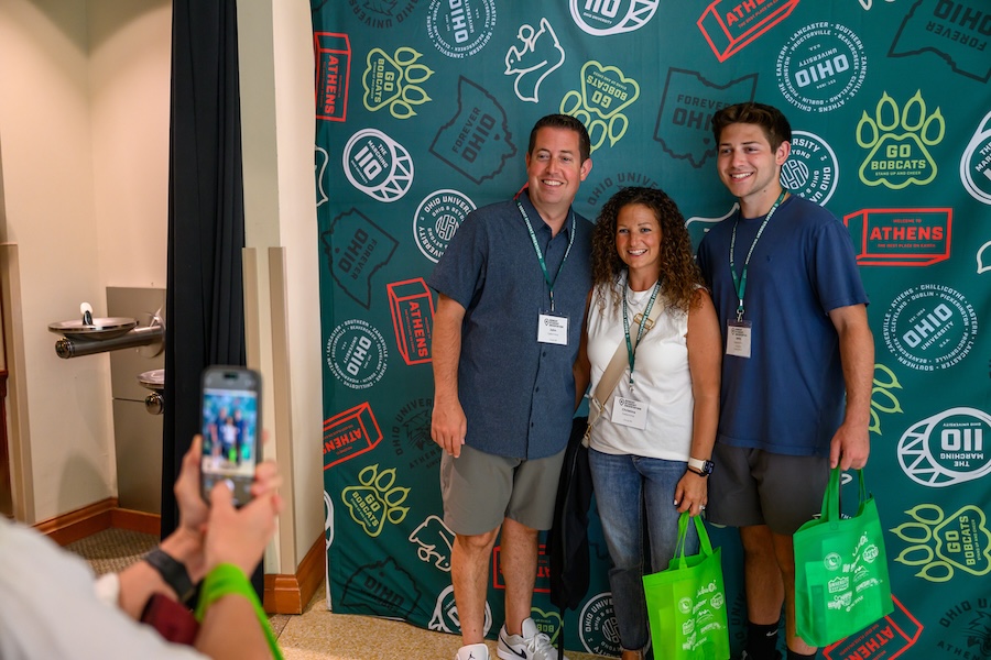 Family poses for photo in front of OHIO backdrop