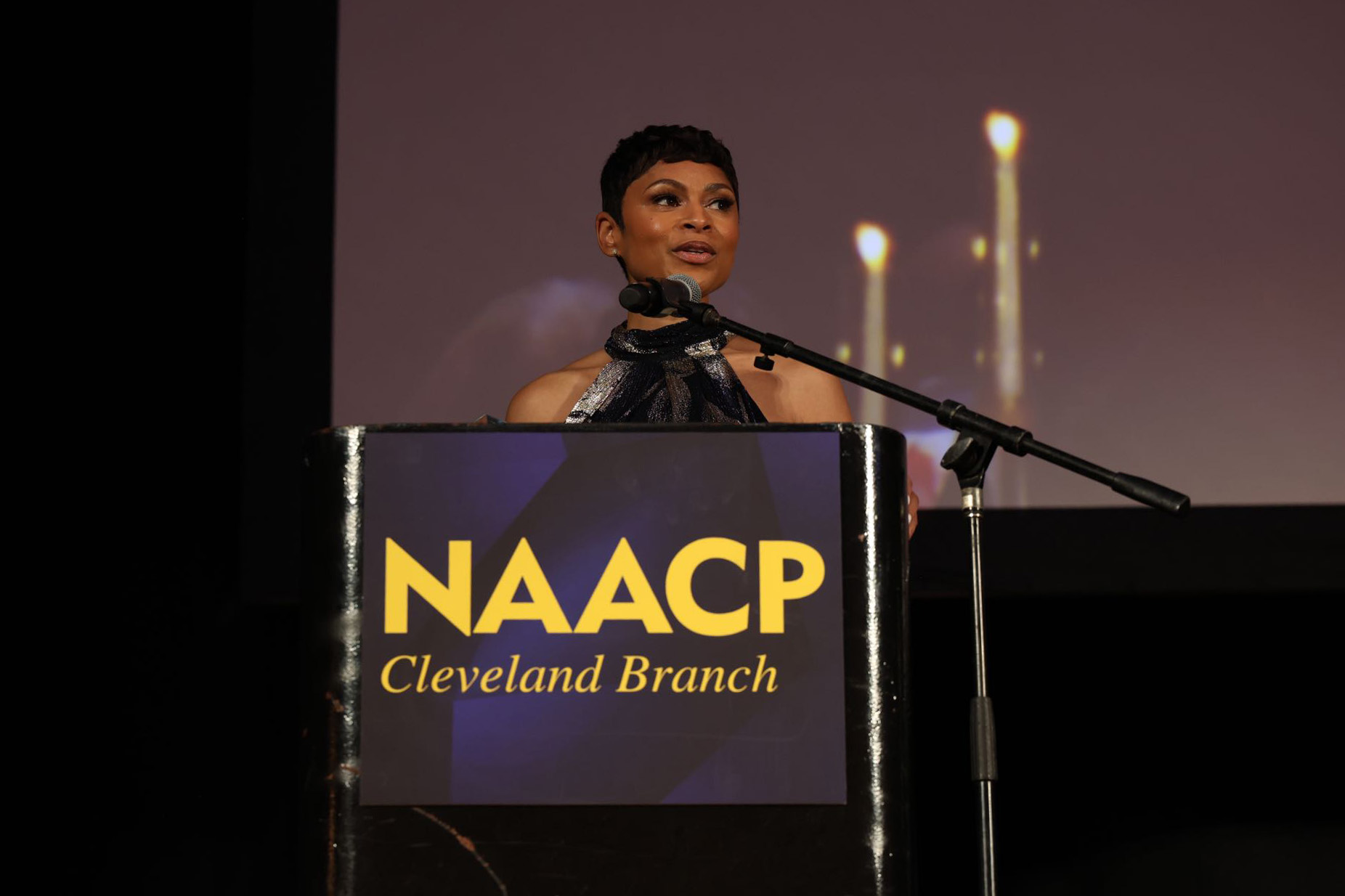 journalist Jericka Duncan stands on stage behind a podium with the NAACP Cleveland Chapter logo