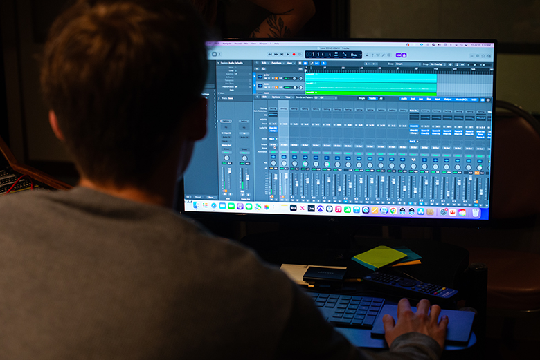 A student adjusts digitized mixing knobs in a digital audio workstation.