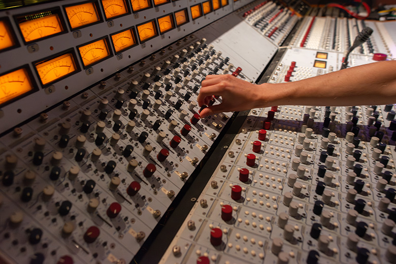 A student adjusts an analog mixing console.