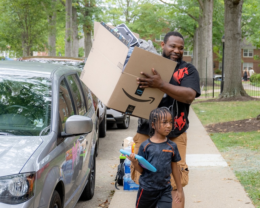 A man and child carry boxes