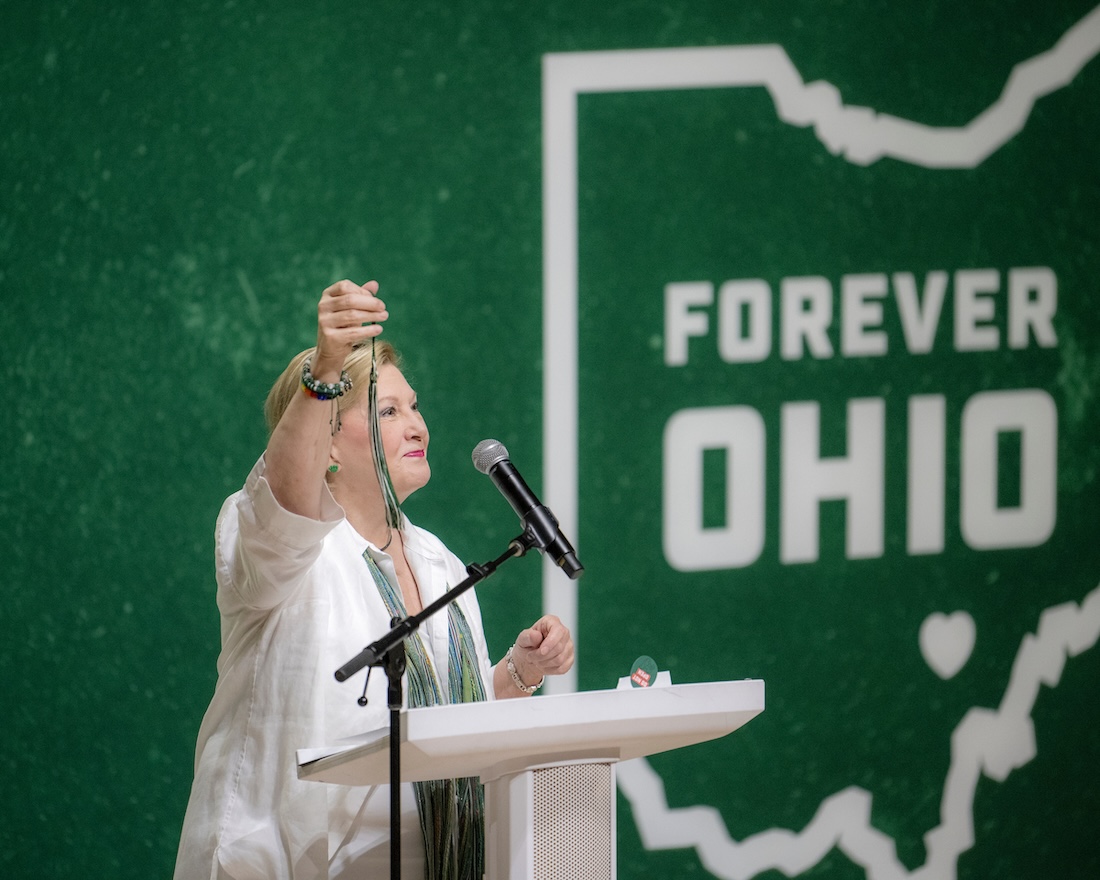 President Lori Stewart Gonzalez holds up a graduation tassel 