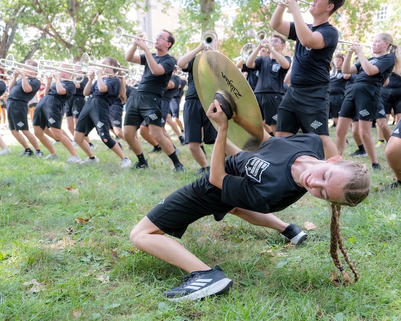 A member of the Marching 110 holds cymbals in a backbend