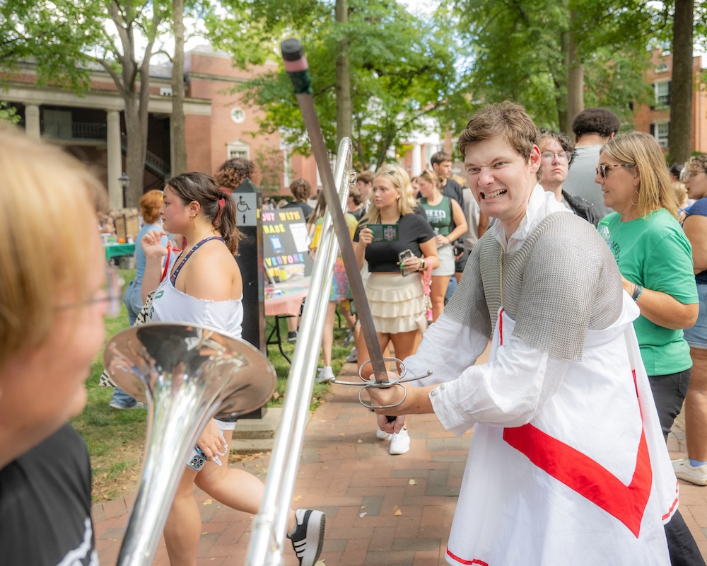 Students in Medieval costumes demonstrate a swordfight