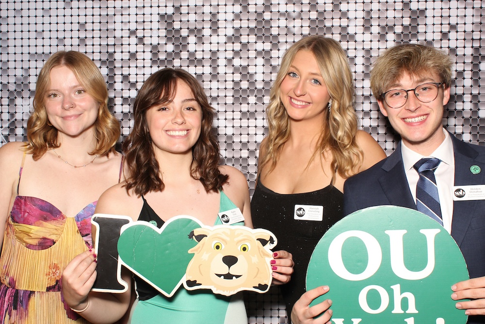 A group of people pose in front of a glittery background, holding OHIO signs
