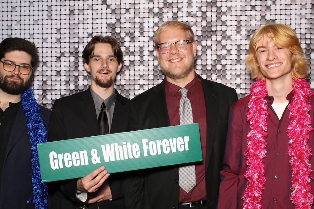 A group of people pose in front of a glittery background, holding OHIO signs