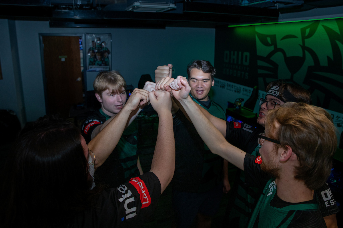 OHIO Esports team huddles together with fist held high