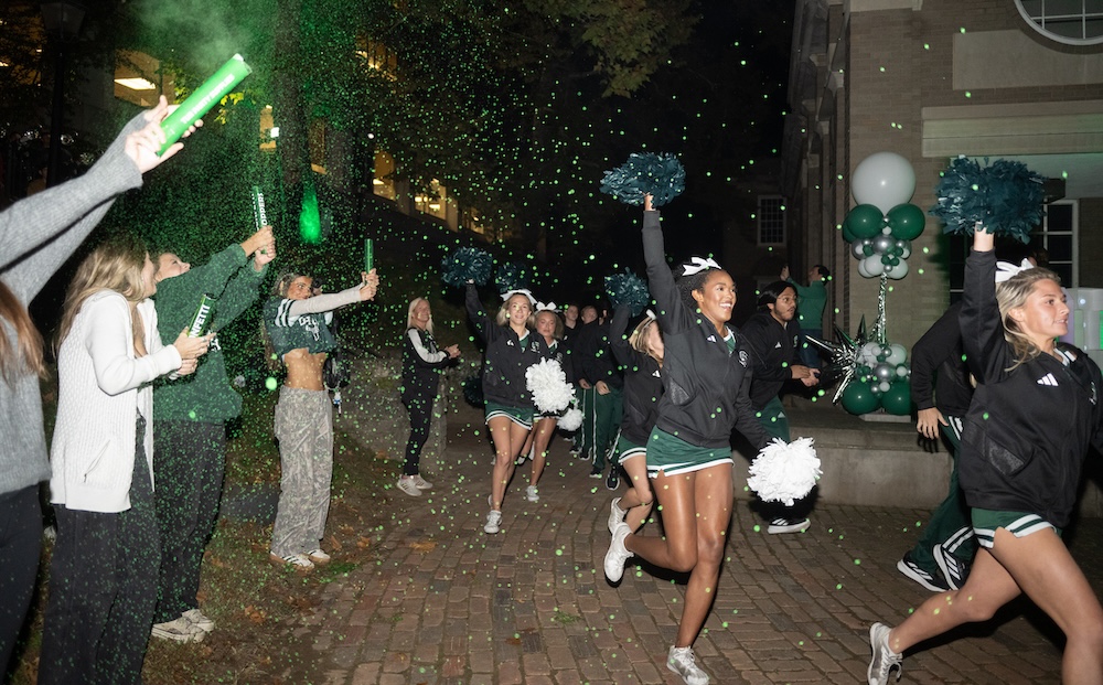 OHIO cheerleaders run through a crowd on College Green at night