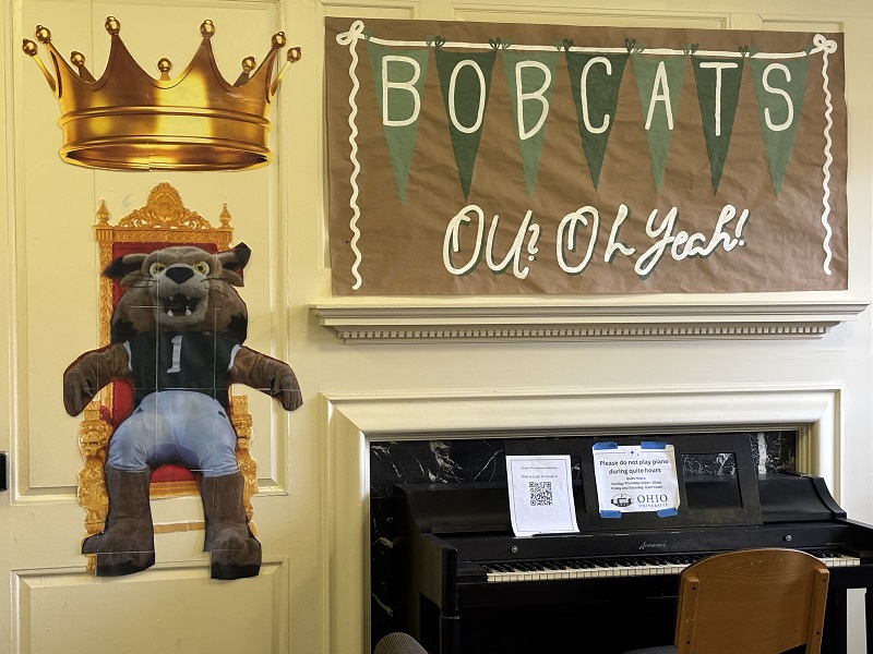 A wall in Tiffin Hall has an image of Rufus sitting on a throne and a crown is over his head, and the wall has a sign that says Bobcats OU? Oh Yeah!