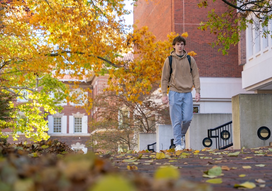 A student walks across campus under the colors of fall