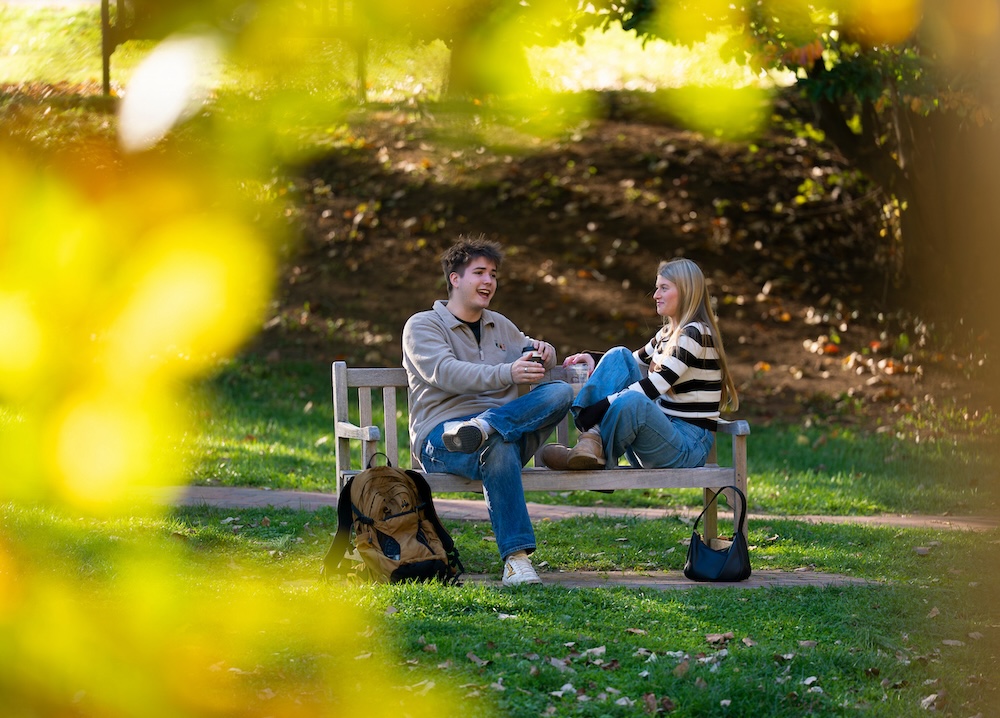 Two students laugh on a park bench