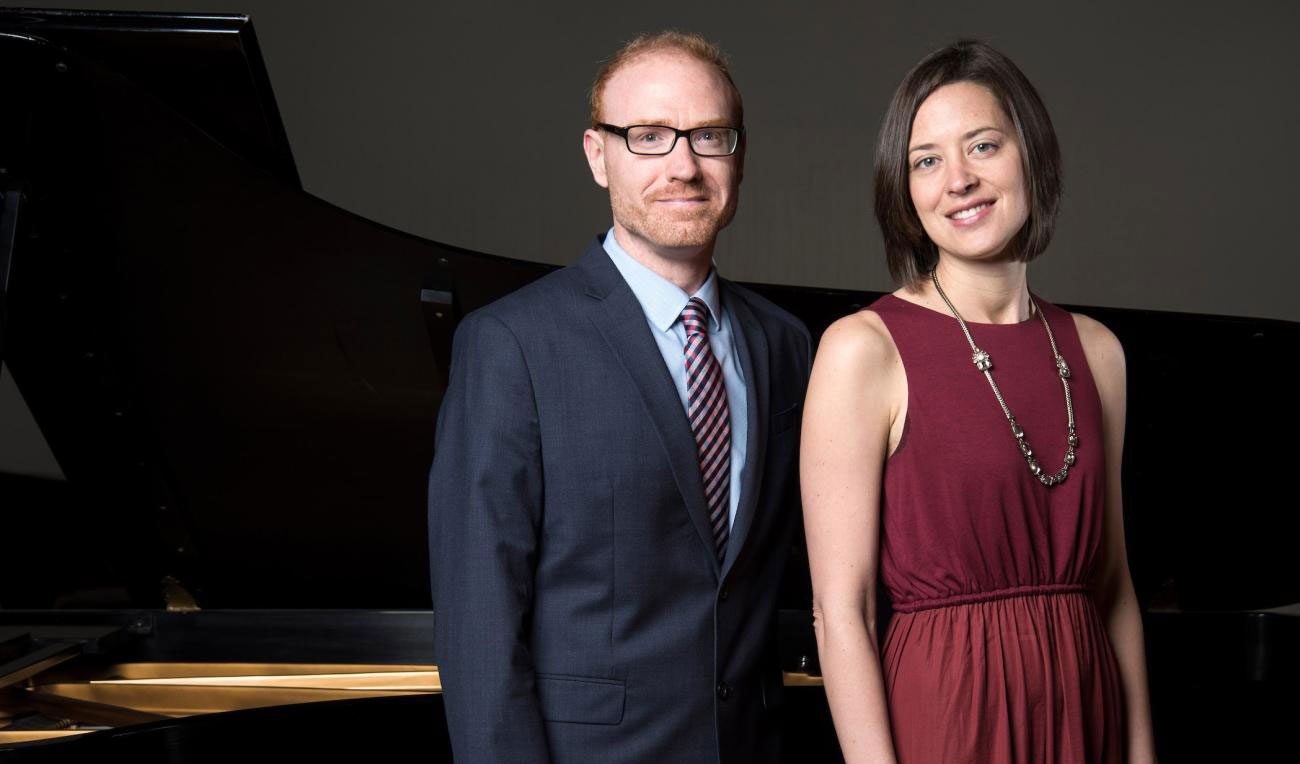 Christopher and Katherine Fisher pose in front of a grand piano