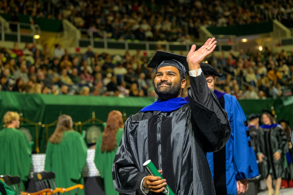 a new graduate waves from the stage of the Convo
