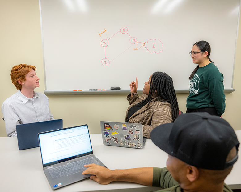Cybersecurity students meet in a group to work through a problem.