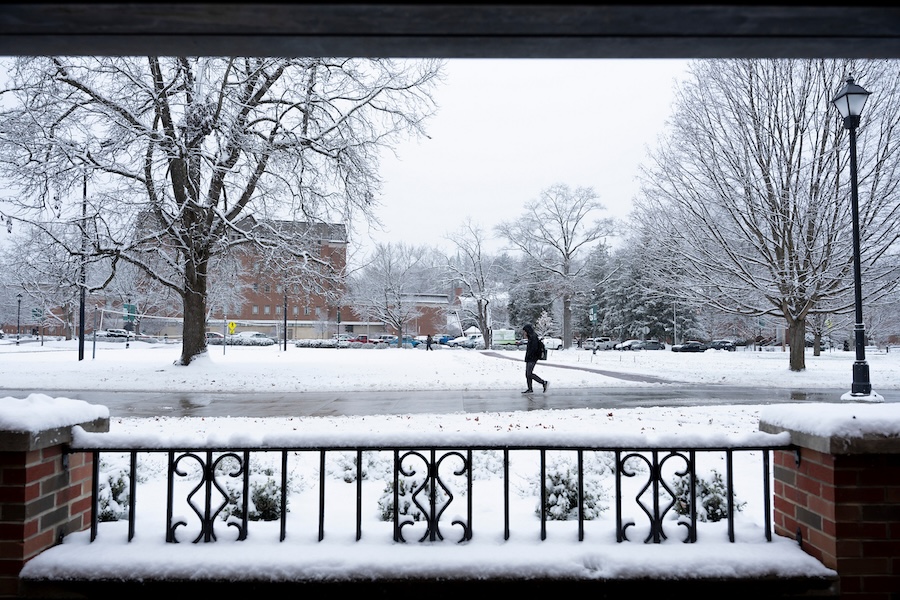 A student walks across campus in the snow