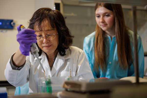 An OHIO researcher conducts a test in a lab while a student watches