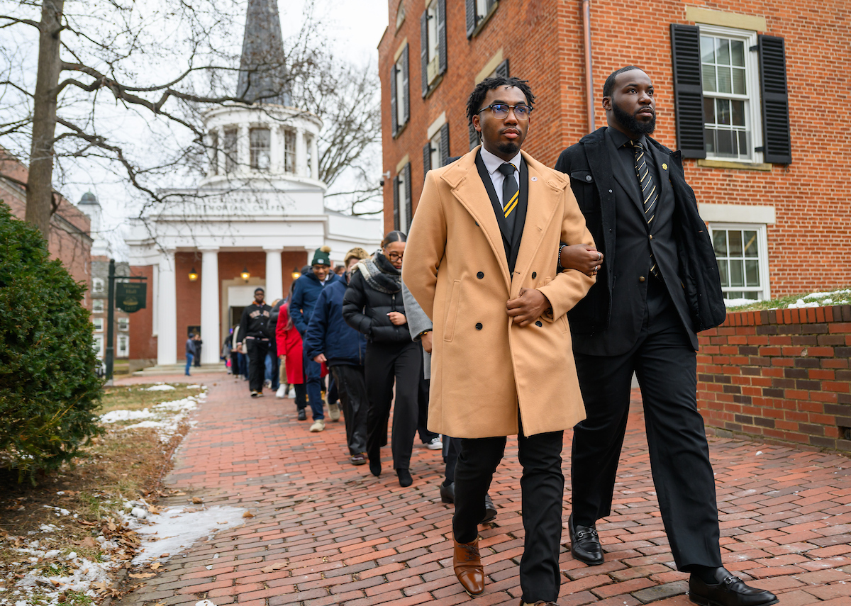 a group marches arm-in-arm across College Green