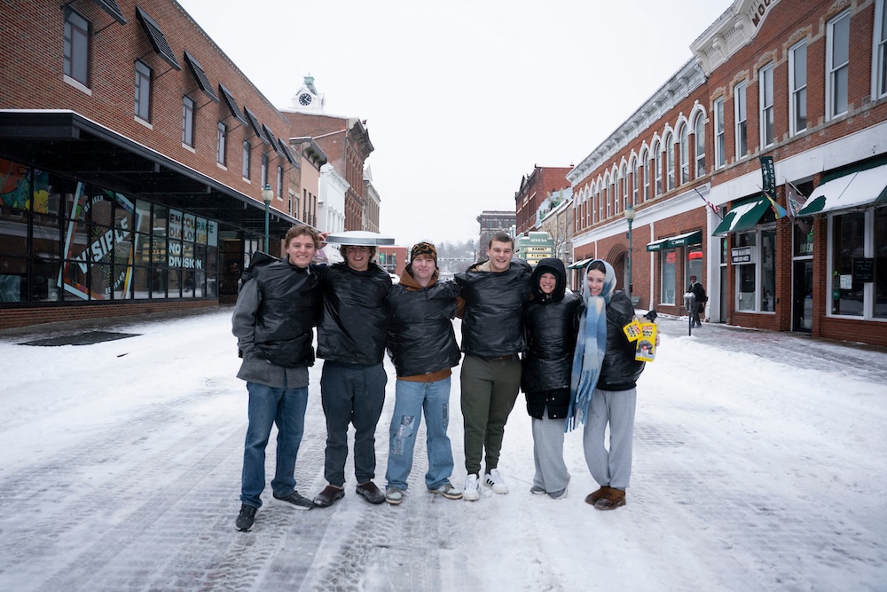 A group of people pose in the middle of a snowy and deserted Court Street