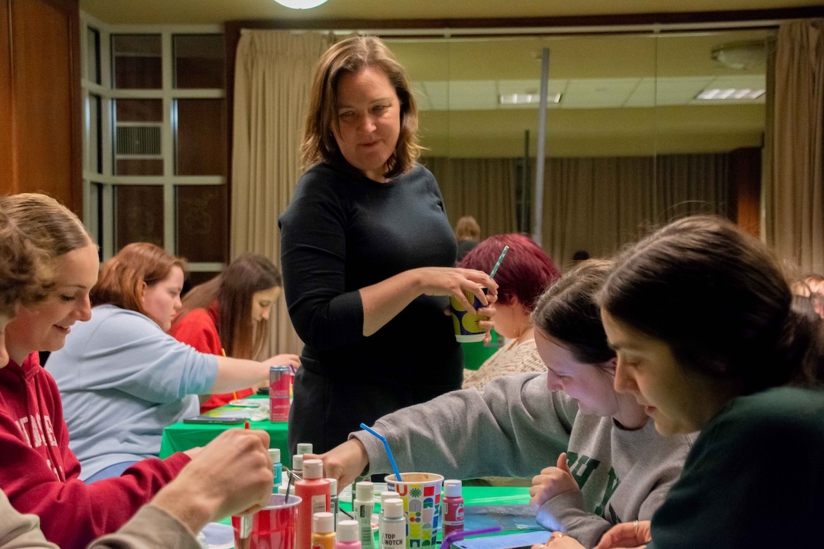 Poet Sarah Green looking at a group of students as they paint. 