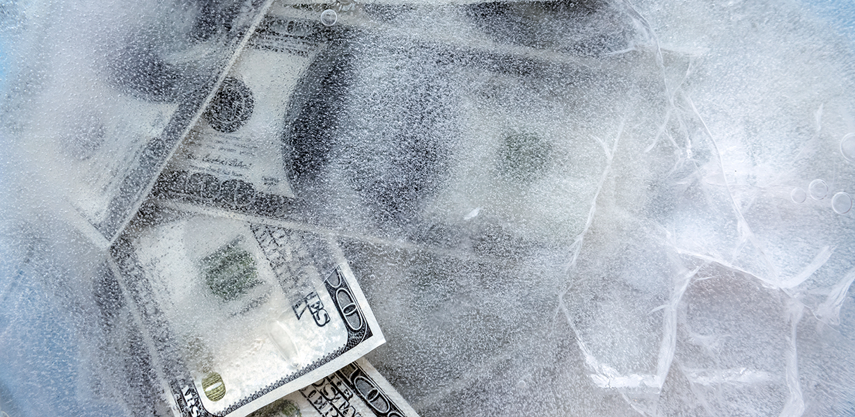 100 dollar bills frozen under a sheet of ice.