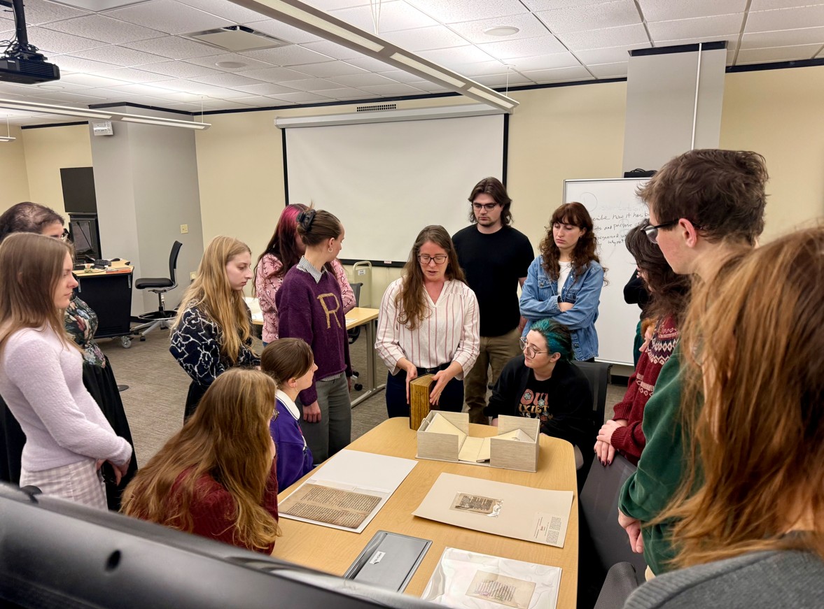 Students gather around a table with written contents on it.