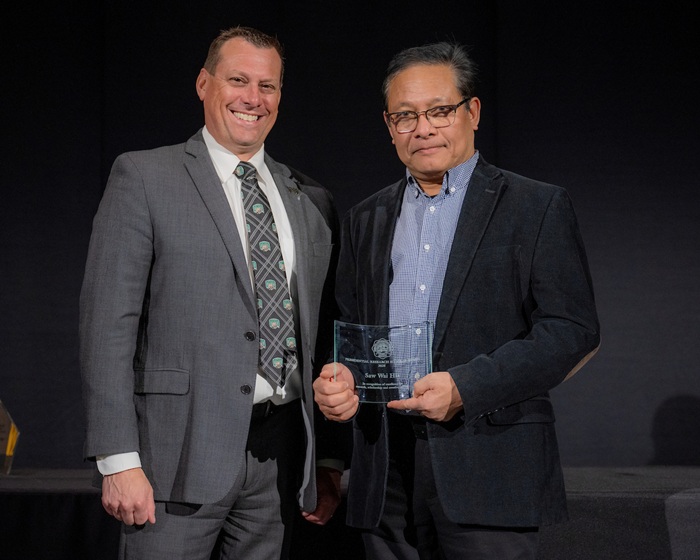 Eric Muth stands with Saw Wai Hla, who is holding the award