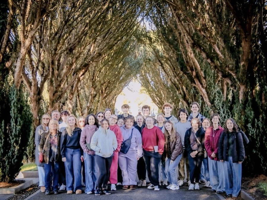 a group of students poses under a canopy of trees