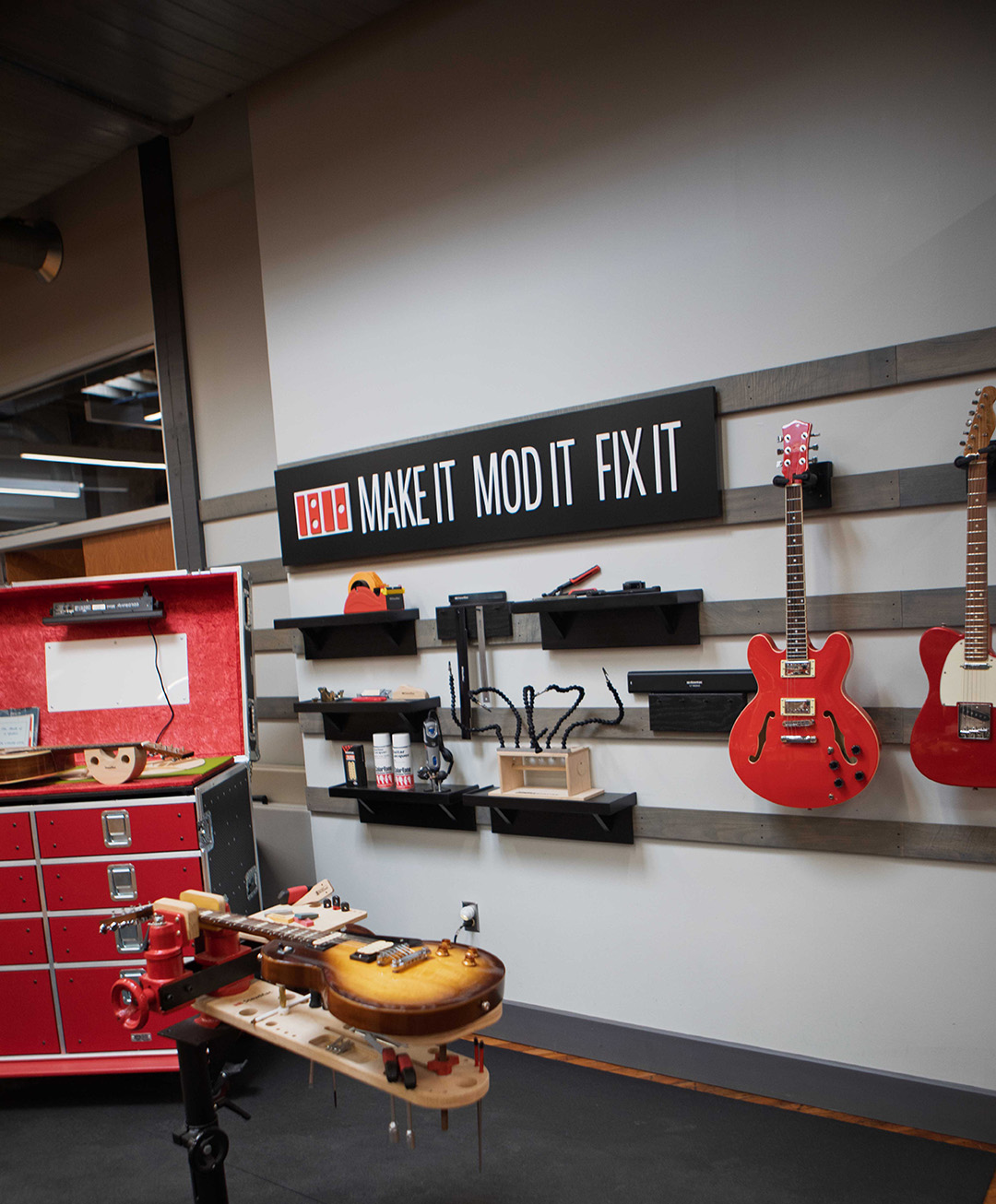 Guitars sit on a work bench and hang on the wall at StewMac.