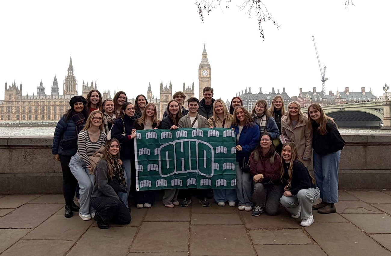 A group of students and faculty pose with Big Ben in the background, displaying an OHIO flag