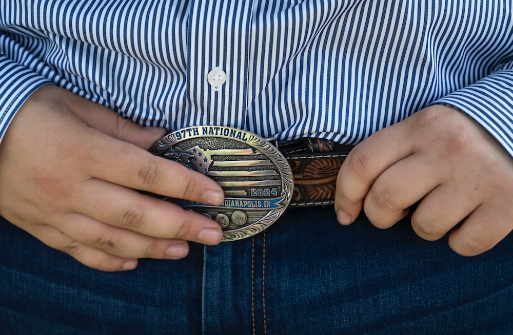 close-up image of a person's hands on a belt buckle over jeans