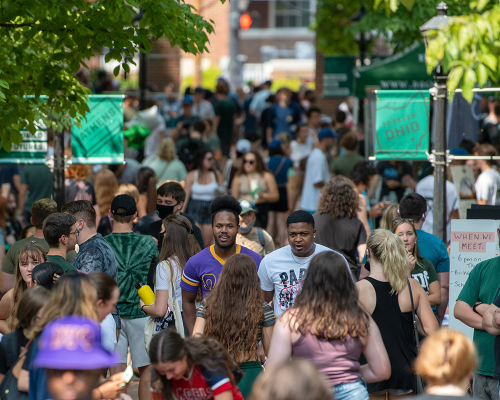 A large group of students walk down the street during an event in Uptown Athens.