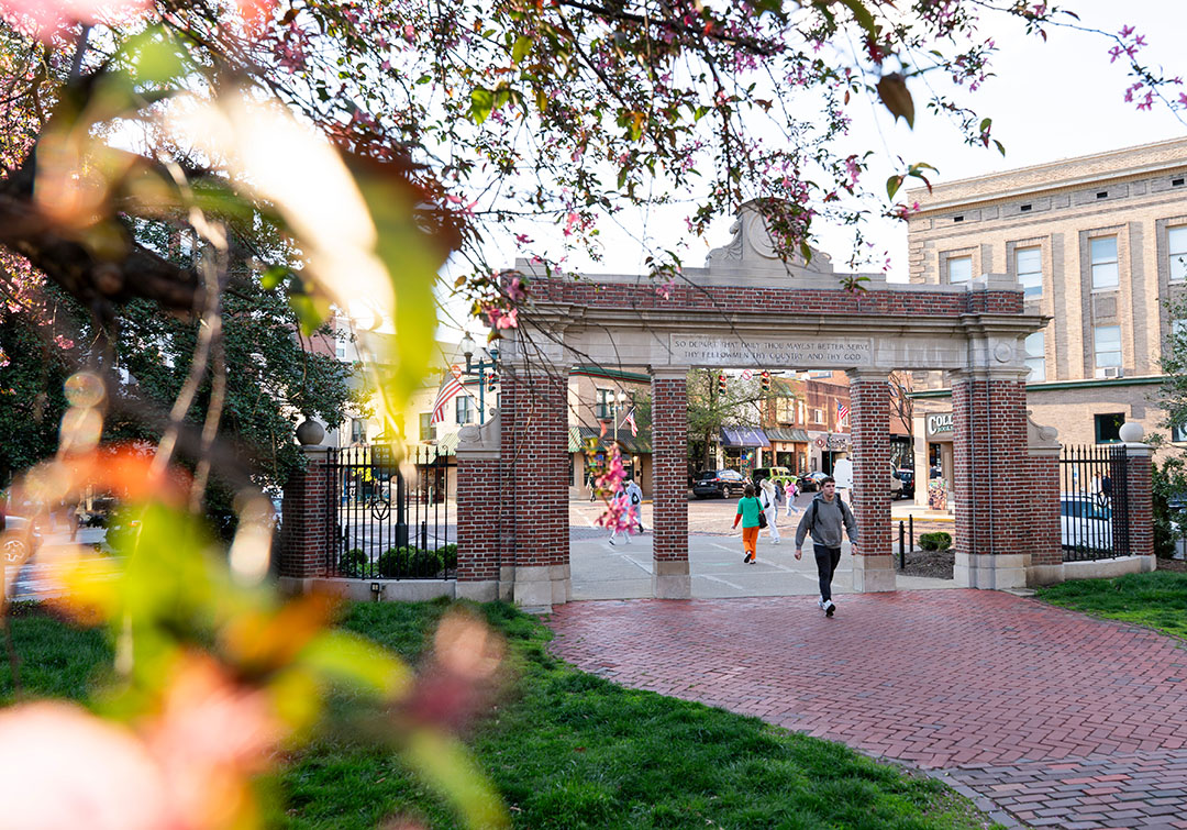 A student walks from Uptown Athens through the Alumni Gateway and onto College Green.