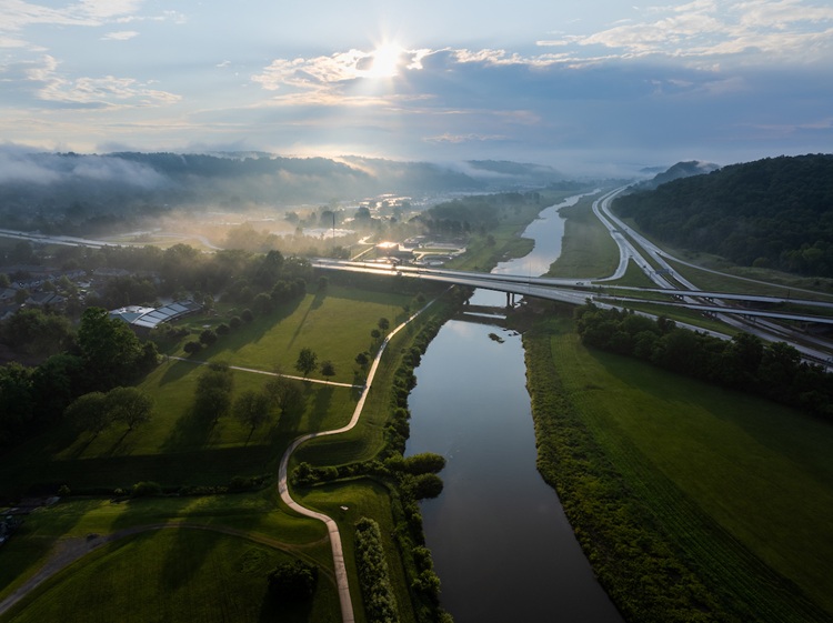 An aerial image of the Hocking River and the highways and hills around it, with the sun shining overhead