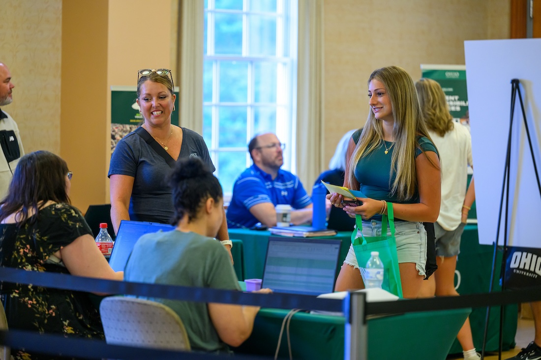 Two women stand in front of a registration table, smiling