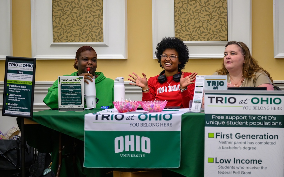 Three people sit at a resource table, the middle one smiles broadly