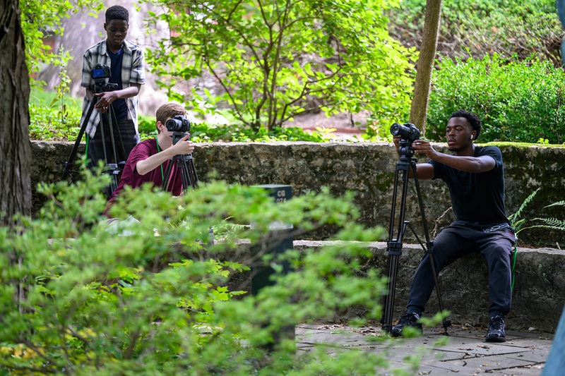 Three camp participants set up cameras while outside on the College Green at Ohio University.