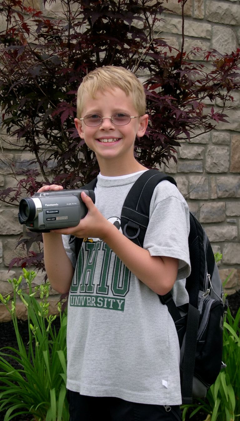 Jack Cowman as a child, posing for a photo with his backpack and camera in hand.