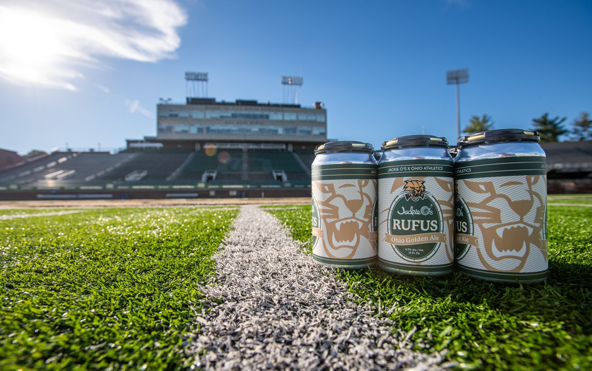 Cans  of the Jackie O's Rufus craft beer are shown on the football field in Peden Stadium