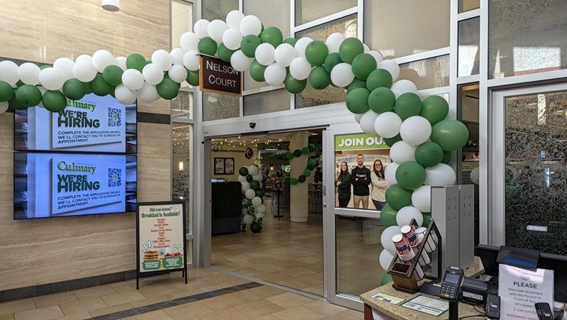 The sign  around Nelson Commons is decorated with green and white balloons