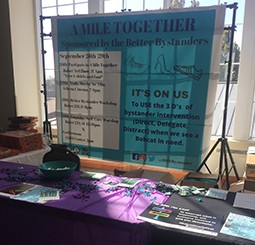 A banner at the kickoff for “A Mile Together” highlights the week’s events as well as tips for being a better bystander.