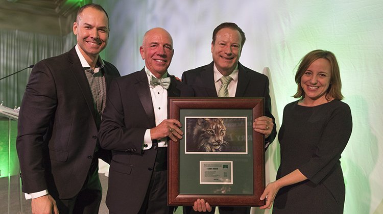 Garry Hunter (second from right) accepts the Glenn C. Randall Lifetime Achievement on behalf of his late brother, Larry Hunter, BSED ’71, MED ’73, from (from left) Russ Eisenstein, director of broadcasting for Ohio Athletics; Tom Davis, chair of the Kermit Blosser Ohio Athletics Hall of Fame Awards Committee; and Julie Cromer, director of Ohio Athletics.