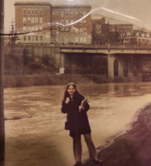 Debby Tinker, BSED ’73, is pictured beside a swollen Hocking River, which at the time ran directly behind Ryors Hall.