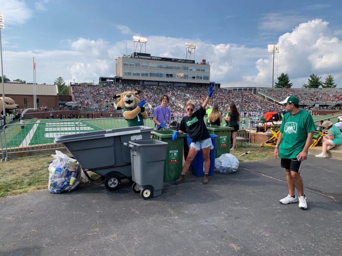  Rufus with Campus Recycling Team Member, Carly Cunningham and a student Rufus Green Team Volunteer gathering and preparing to sort recyclables inside Peden stadium.