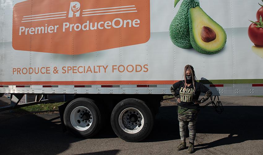 Roshelle Pate poses for a photo in front of one of the trucks that delivered palettes of fresh food for free drive-through grocery distributions that were held in Athens in October. 