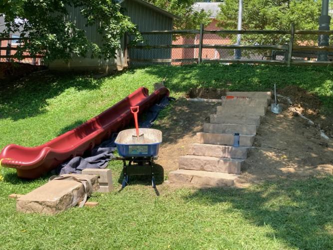 Stone steps and a slide being installed into a hillside