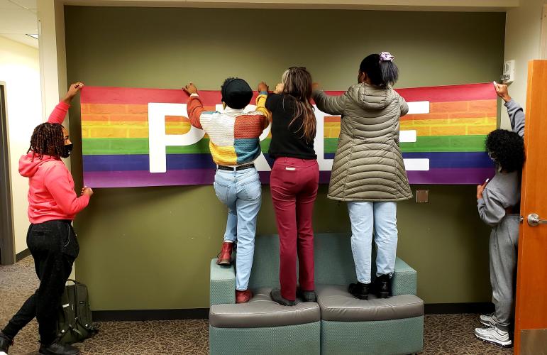 Students hang a sign in the new LBGT Center