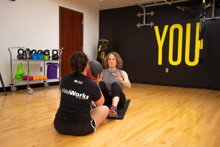 Well Works trainer and trainee tossing a yoga ball back and forth