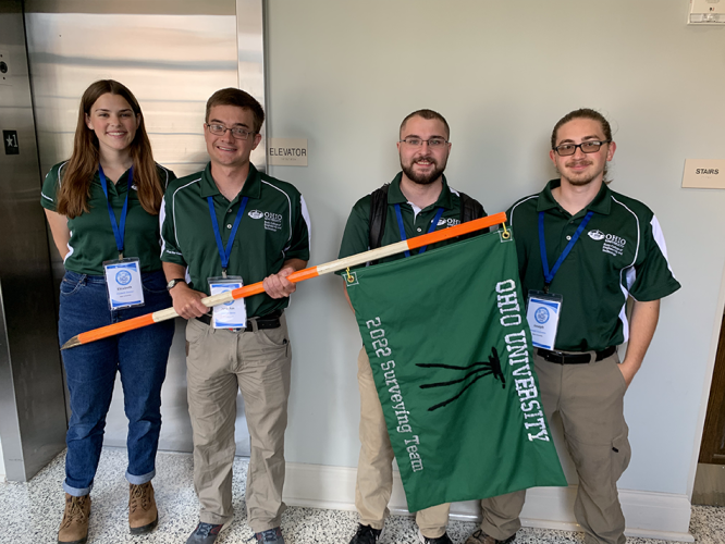 Liz Zimmer, Jonathan Beiter, Garrett Spargur, and Joe Cusimano pose with a surveying flag.