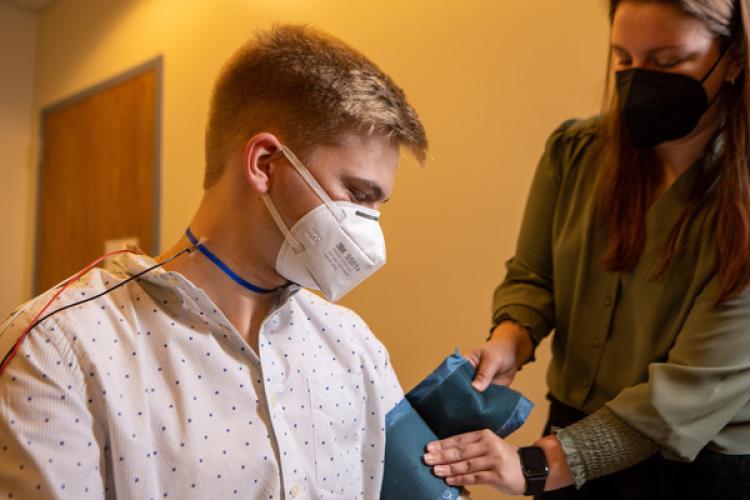 Graduate student Abriana Gresham gets senior psychology major Nash Randall ready to demonstrate how data like heart rate is collected during their experiments.